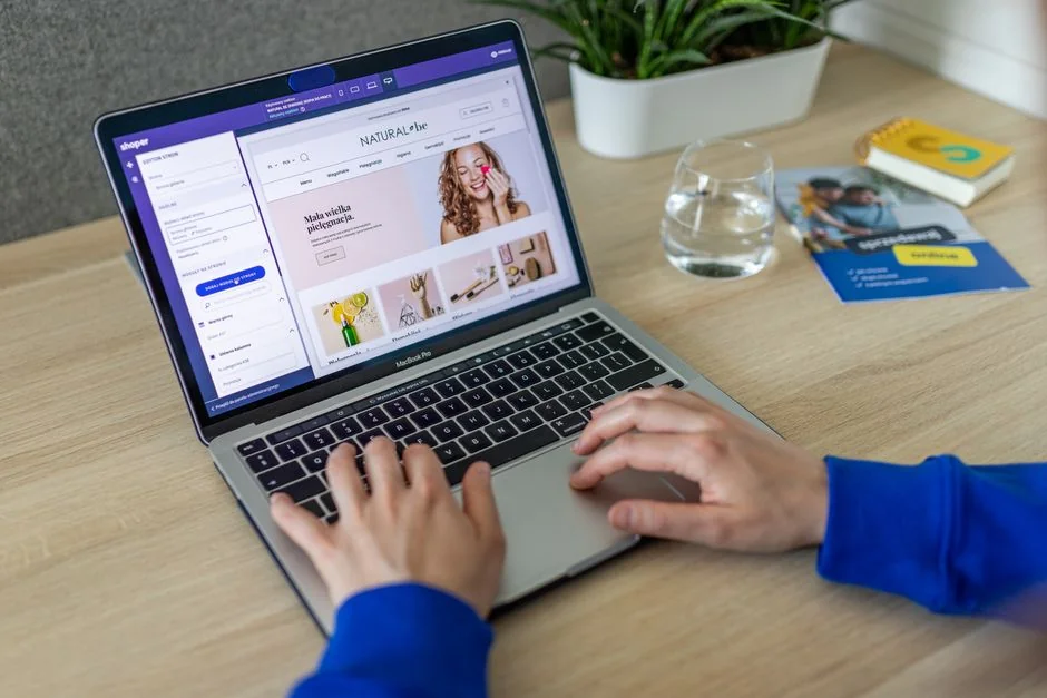 Vue rapprochée de mains interagissant avec un site e-commerce sur l’écran d’un ordinateur portable en intérieur.